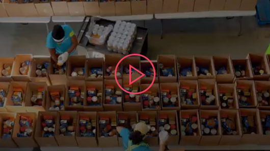 DailyBread video thumbnail – three rows of boxes filled with canned food and volunteers organizing around them