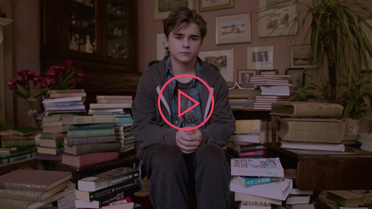 Toronto Library video thumbnail – a boy sitting in a room surrounded by books